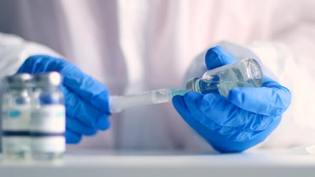 Doctor wearing protective gloves holding a syringe and preparing for covid 19 or vaccine injection. Development and creation of a vaccine