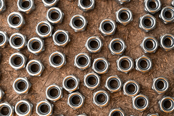Heap of stainless screw-nuts on wooden background. Background