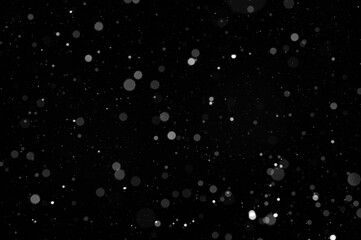 Bokeh of white snow on a black background. Snowfall - design element.
