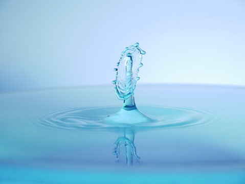 Gouttes d'eau pr&eacute;sentant des motifs abstraits lors de la collision. Fond blanc et bleu.