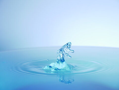 Gouttes d'eau pr&eacute;sentant des motifs abstraits lors de la collision. Fond blanc et bleu.