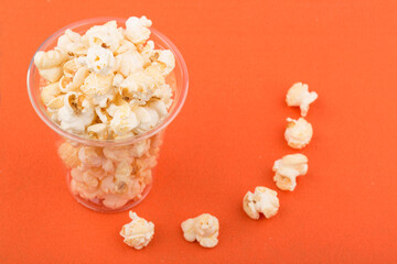 Heap of delicious salty popcorn, isolated on orange background.