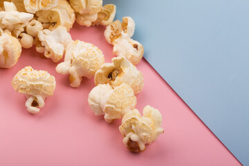 Obraz na płótnie Canvas Heap of delicious salty popcorn, isolated on pink and blue background.
