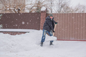 Snow collapse, man cleaning snow at winter weather with a shovel on a yard, winter trouble concept
