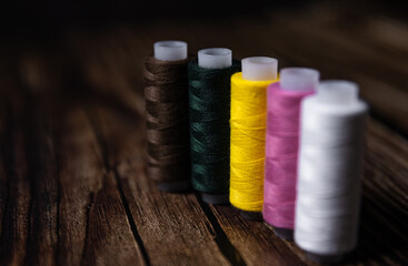Sewing threads on a wooden background. A set of bobbin threads. Vintage tabletop sewing accessories