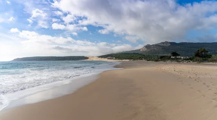 Foto op Plexiglas Bolonia strand, Tarifa, Spanje vredig leeg gouden zandstrand met rollende golven en dennenbos en een grote zandduin op de achtergrond