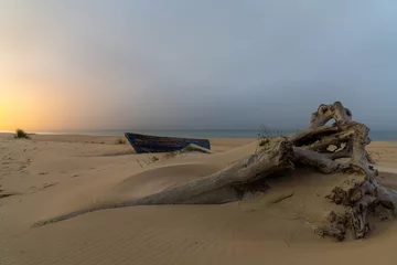 Papier Peint photo autocollant Plage de Bolonia, Tarifa, Espagne vieux bateau de pêche en bois et bois flotté sur une plage après le coucher du soleil avec les lumières du village derrière