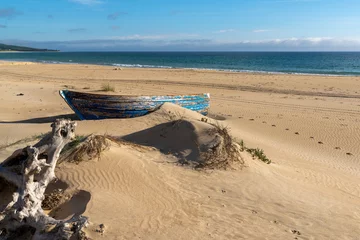 Fotobehang Bolonia strand, Tarifa, Spanje old wooden fishing boat and driftwood on a beach