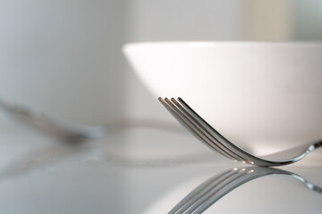 Fork and spoon with white dish on white marble texture background. Concept for food and dining...