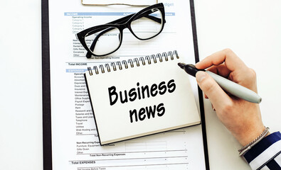 BUSINESS NEWS text written by business woman in her diary on office desk.