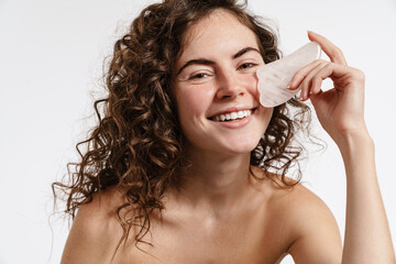 Smiling shirtless girl doing facial massage with gua sha stone