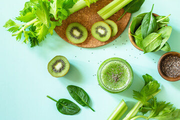 Healthy diet and nutrition, vegan, alkaline, vegetarian concepts. Green smoothie with celery, kiwi and spinach on a green background. Top view flat lay.