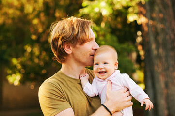 Outdoor portrait of happy young father with adorable baby