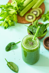 Healthy diet and nutrition, vegan, alkaline, vegetarian concepts. Green smoothie with celery, kiwi and spinach on a green background.