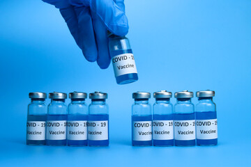 The doctor holds a coronavirus vaccine in hand on a blue background. The concept of the fight against ncov COVID-19 pandemic