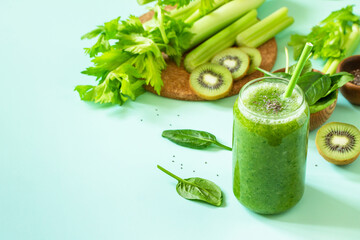 Healthy diet and nutrition, vegan, alkaline, vegetarian concepts. Green smoothie with celery, kiwi and spinach on a green background. Copy space.