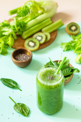 Healthy diet and nutrition, vegan, alkaline, vegetarian concepts. Green smoothie with celery, kiwi and spinach on a green pink background.