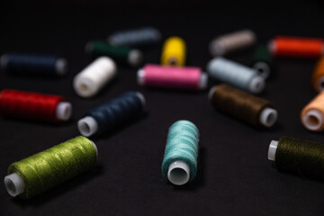 colored threads are scattered on a dark background. Side view