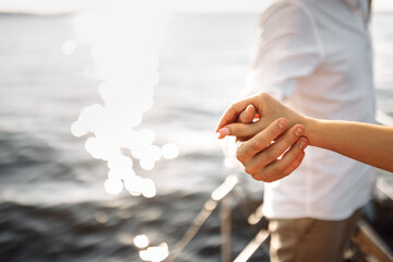 Hands of a couple in love on a yacht in the blue sea
