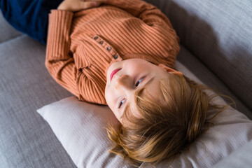 Young boy is lying on the couch and looking aside.  Toddler falling sick and relaxing on the sofa....