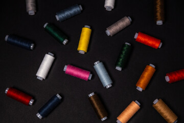 colored threads are scattered on a dark background. View from above.