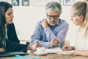 Family legal advisor explaining document details to mature father and adult daughter. Medium shot. Expertise or paperwork concept