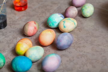 Dozen colored home-made Easter colored eggs on table and paints