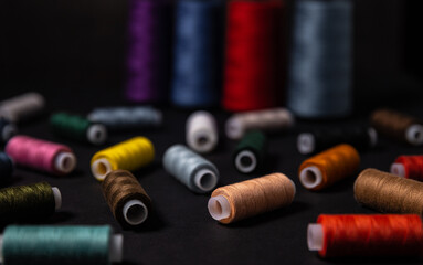 Multi-colored threads are scattered on a dark background. Selective focus