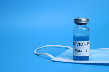 Glass vial with coronavirus vaccine on blue background
