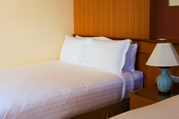 Simple bulb lamp and bed with white pillow of brown background - Hotel bed with space for text and beautiful