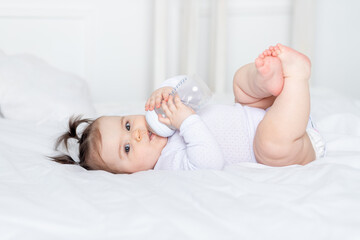 baby with a bottle on the bed at home, baby food concept
