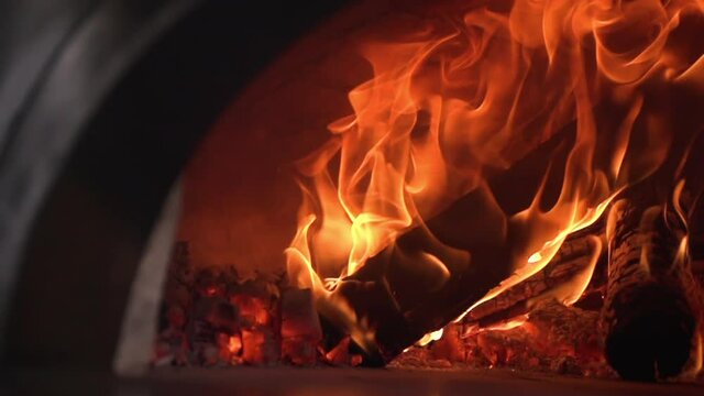 Warm burning wooden blocks in a professional oven with a metal arch on the front plan. Fragments that emit violent sparks