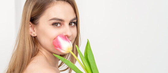 Obraz na płótnie Canvas Beautiful caucasian young woman with one tulip against a white background