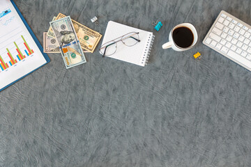 Office supplies, money, documents, keyboard on a gray background.