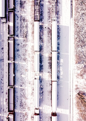 Top view of cargo trains. Aerial view from flying drone of snow covered freight trains on the railway station. Wagons with goods on railroad with on man the middle. Industrial conceptual scene.