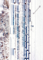 Top view of cargo trains. Aerial view from flying drone of snow covered freight trains on the railway station. Wagons with goods on railroad.