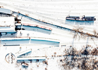 Top view of cargo trains and locomotive depot. Aerial view from flying drone of snow covered freight trains on the railway station.