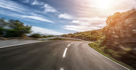 Empty long mountain road to the horizon on a sunny summer day at bright sunset