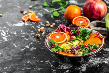 Fototapeta na wymiar Healthy vegetarian buddha bowl salad avocado, persimmon, blood orange, nuts, spinach, arugula and pomegranate, top view