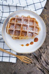 Fresh homemade waffles with caramel syrup in a white plate
