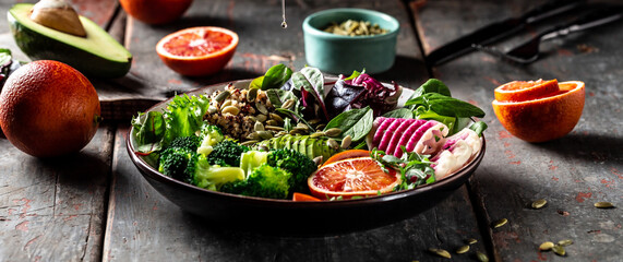 Healthy vegetable buddha bowl lunch avocado, blood orange, broccoli, watermelon radish, spinach, quinoa, pumpkin seeds. Balanced food. Delicious detox diet