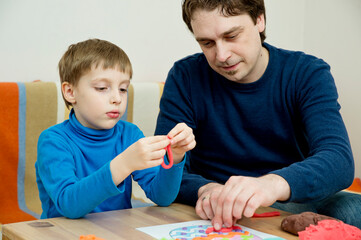 Small motor skills. dad and boy decorate Easter egg with play dough