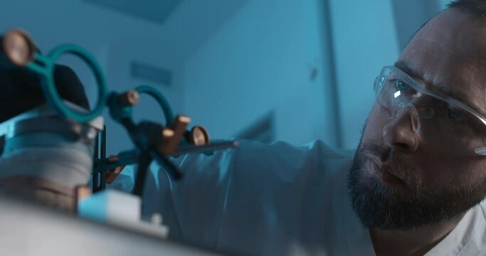A model of an upper jaw in axiograph face-bow is standing on the table in a dark dentist`s office; a male medical worker is sitting next to it, checking and exploring the device.