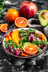 Fototapeta na wymiar Vegan, detox Buddha bowl with avocado, persimmon, blood orange, nuts, spinach, arugula and pomegranate. Healthy balanced eating. Top view. vertical image