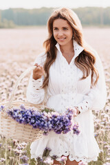 girl in the field with a bouquet of flowers in a basket in nature