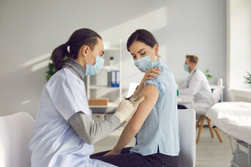 Vaccination campaign during global Covid 19 pandemic. Young woman gets vaccinated at clinic or...