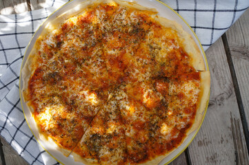 Pizza cheese in a white plate placed on a wooden table 