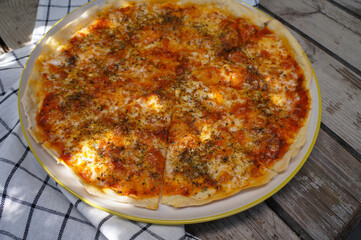 Pizza cheese in a white plate placed on a wooden table 