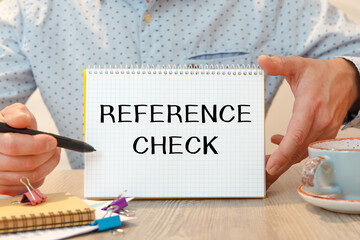 Notebook with text - REFERENCE CHECK - near office supplies.