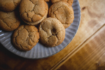 a delicious looking batch of snickerdoodle cookies and some warm milk in a rustic looking cup. the cookies are freshly baked and have   Cinnamon and sugar on them. the cow milk is fresh and warm. 
